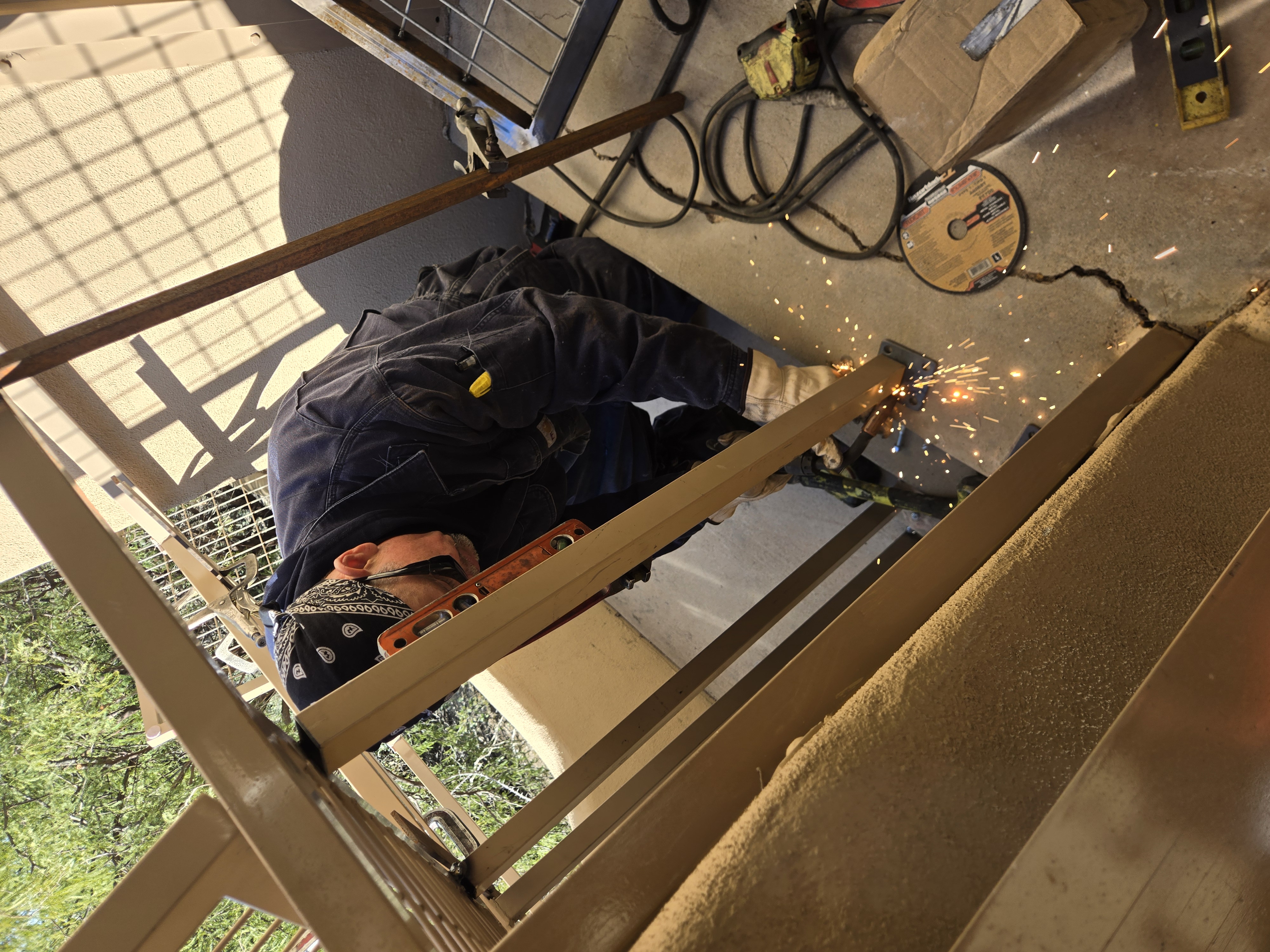 Welder in bandana using grinder with shower of sparks on the lower frame